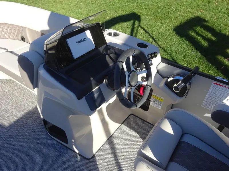 Slide: The Image of 2024 Harris Sunliner 210 boat dashboard with steering wheel and Simrad display. - 14