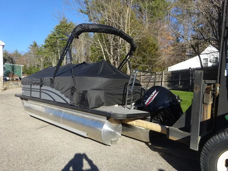 Slide: The Image of 2024 Harris Sunliner 210 pontoon boat with cover and Mercury outboard motor on trailer. - 4