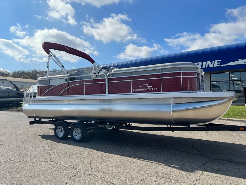 The Image of 2023 Bennington SV Line pontoon boat on a trailer under a blue sky. - 0