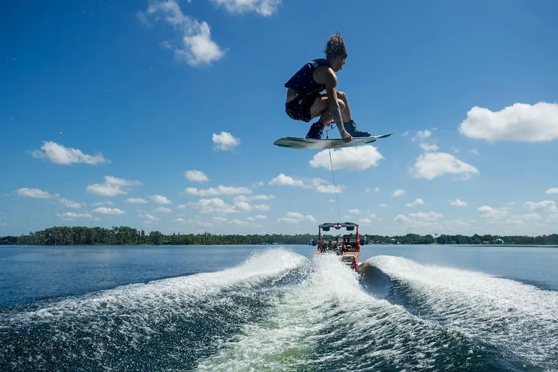 Slide: The Image of Wakeboarder performing a jump behind a 2023 Nautique Super Air Nautique G25 Paragon boat. - 38