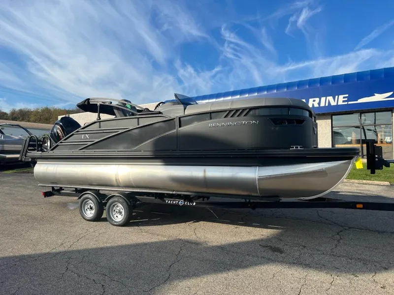 Slide: The Image of 2023 Bennington LX Sport Line pontoon boat on a trailer outside a marine dealership. - 0