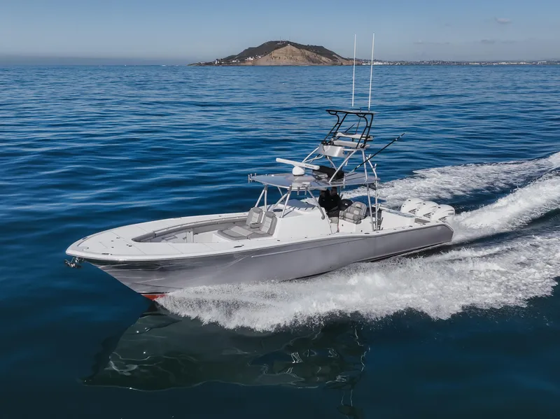 Slide: The Image of 2019 Buddy Davis 42 CC boat cruising on open water near a distant island. - 2