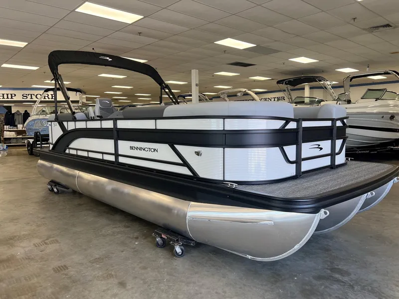 Slide: The Image of 2024 Bennington S Line pontoon boat in showroom, sleek design, black and white color scheme. - 0