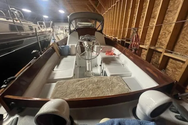 Slide: The Image of 1966 Tripp 31 Masthead Sloop in a wooden boathouse, showcasing its deck and steering wheel. - 15