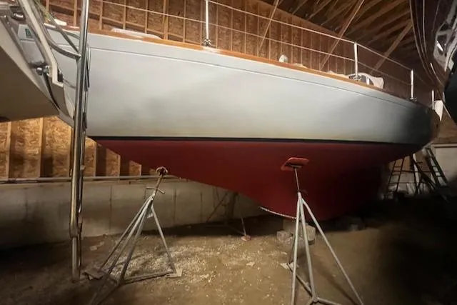Slide: The Image of 1966 Tripp 31 Masthead Sloop in storage, supported by stands, with red hull. - 22