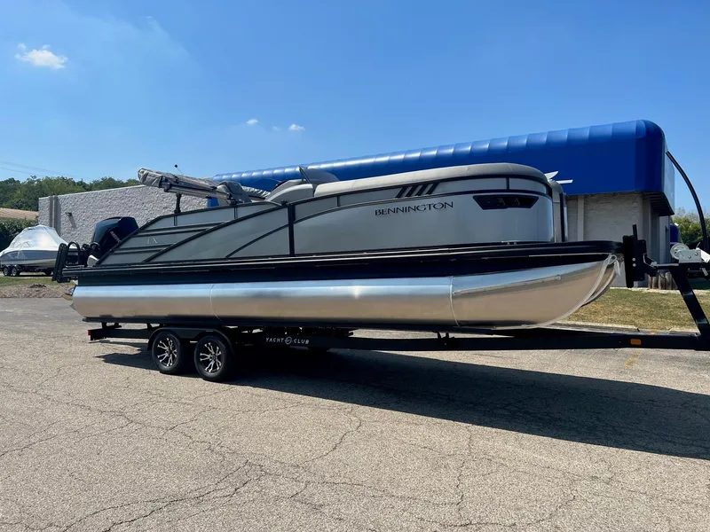 The Image of 2024 Bennington LX Sport Line pontoon boat on trailer under clear blue sky. - 0