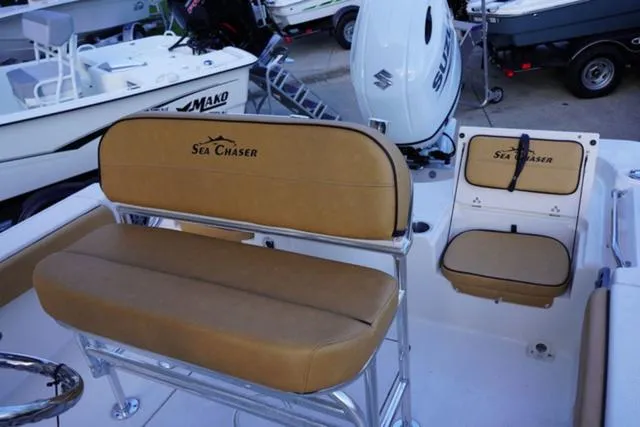 Slide: The Image of 2024 Sea Chaser 21 LX boat interior with tan seating and Suzuki outboard motor. - 12