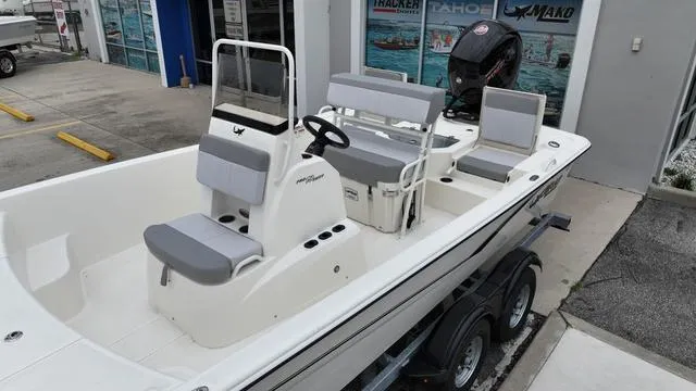 Slide: The Image of 2023 Mako 19 Pro Skiff boat with seating and console, parked on a trailer. - 11