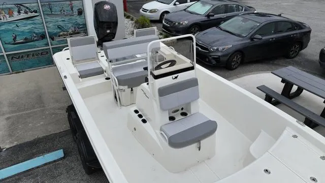 Slide: The Image of 2023 Mako 19 Pro Skiff boat with seating and console, parked near cars. - 12