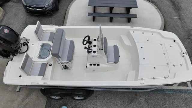 Slide: The Image of 2023 Mako 19 Pro Skiff boat with seating and steering console, parked on a trailer. - 13