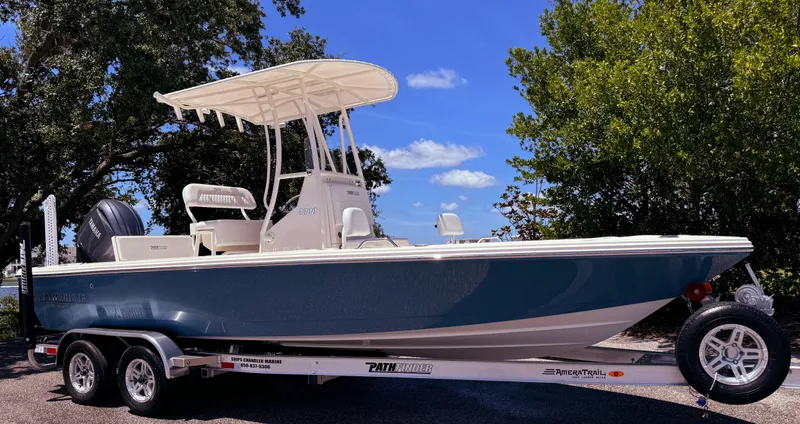 The Image of 2025 Pathfinder 2200 TRS boat on trailer, parked outdoors under clear blue sky. - 0
