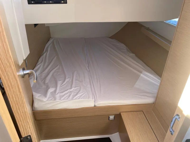 Slide: The Image of 2024 Hanse 410 yacht cabin with a neatly made bed and wooden interior. - 29