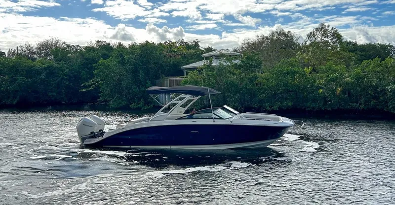 Slide: The Image of 2023 Sea Ray SDX 290 Outboard boat cruising on a river with lush greenery. - 5