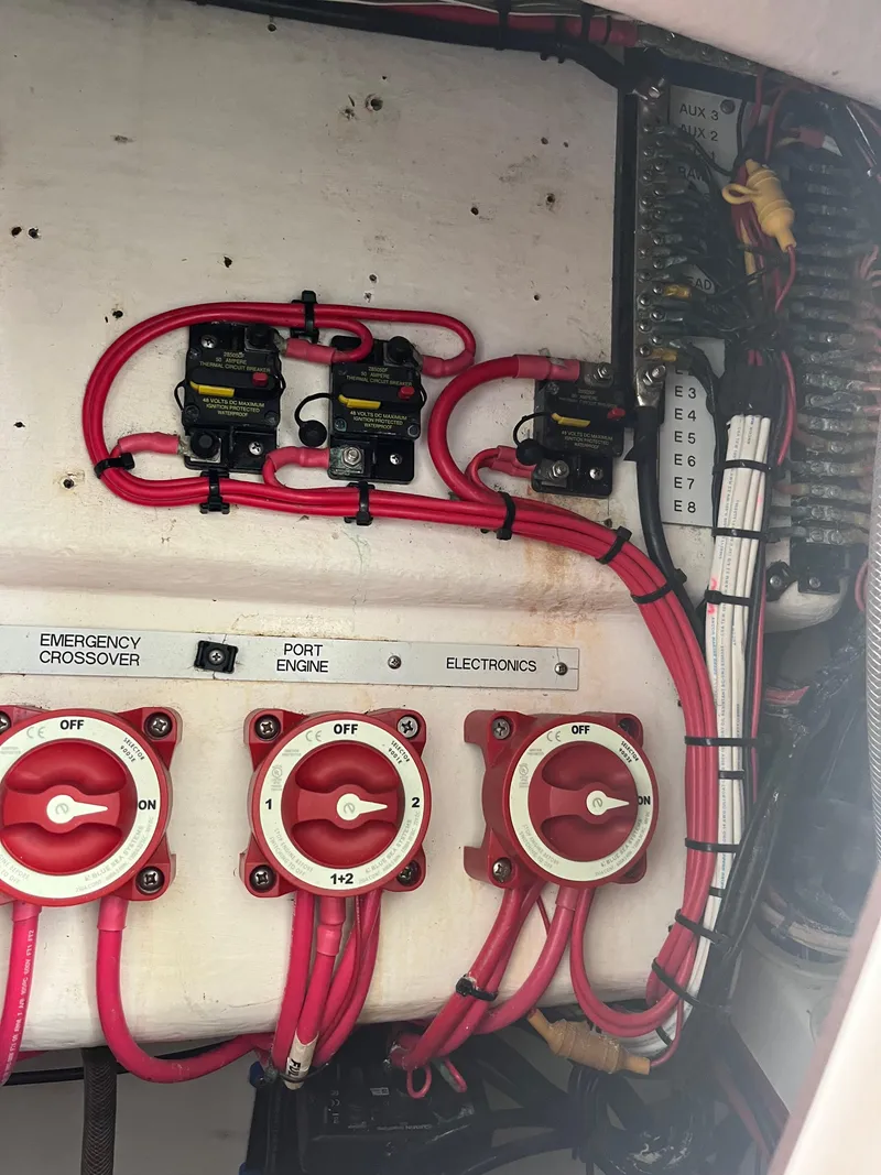 Slide: The Image of Electrical panel of a 2004 Venture 34 Center Console boat with red wiring and switches. - 12