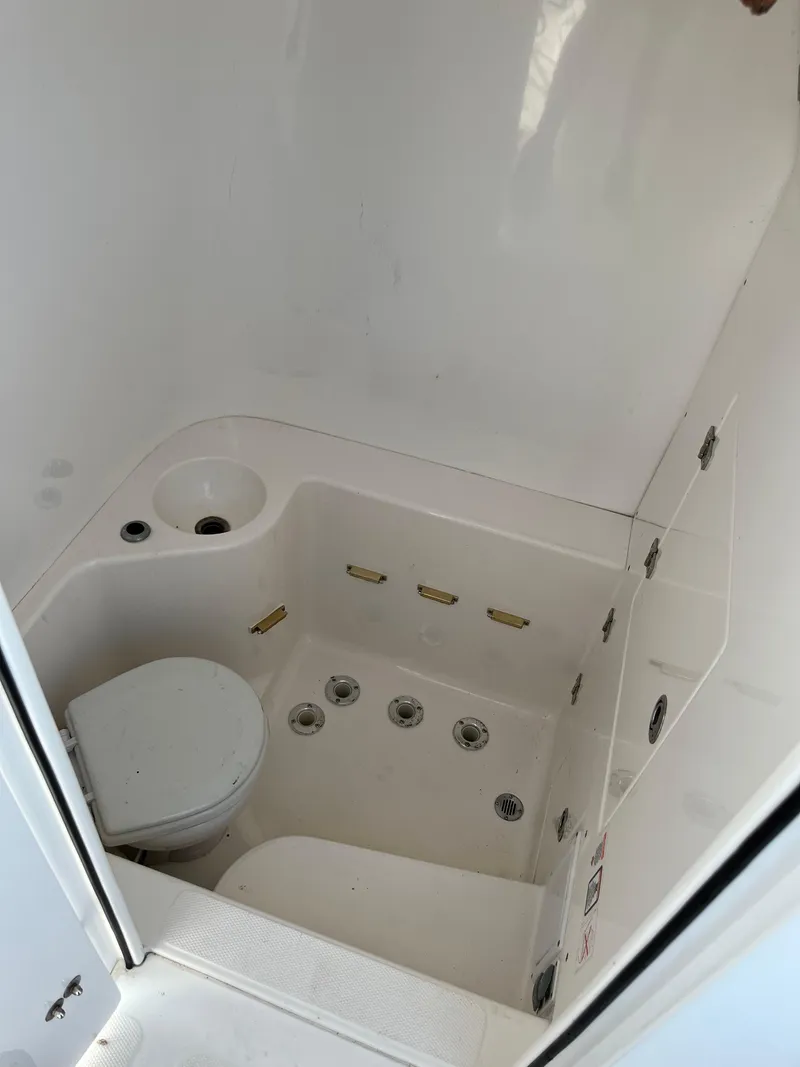 Slide: The Image of 2004 Venture 34 Center Console boat bathroom with toilet and storage compartments. - 7