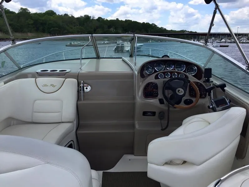 Slide: The Image of 2001 Sea Ray 280 Sundancer cockpit with white seating and wood-accented steering wheel. - 15