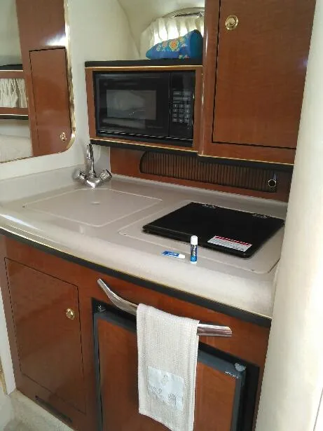 Slide: The Image of 2001 Sea Ray 280 Sundancer galley with microwave, sink, and storage cabinets. - 27
