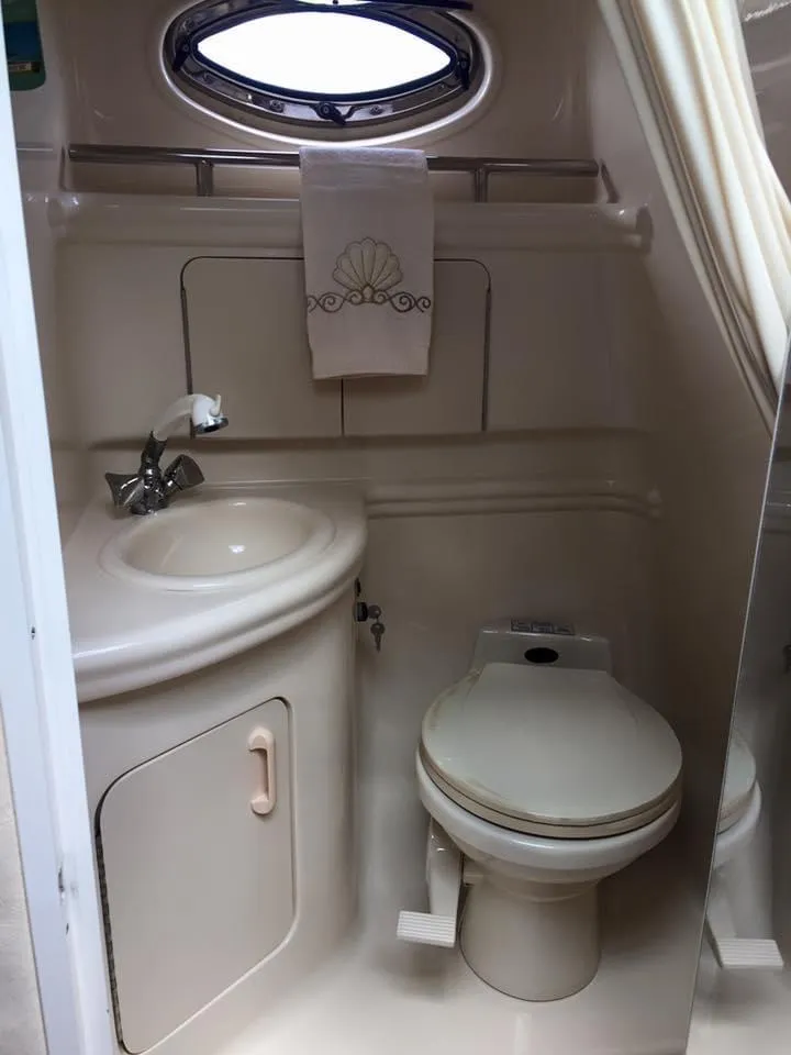 Slide: The Image of 2001 Sea Ray 280 Sundancer bathroom with sink, toilet, and porthole window. - 8