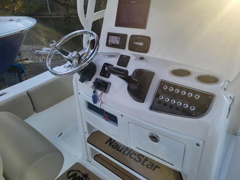 Slide: The Image of 2021 NauticStar 2302 Legacy boat console with steering wheel, controls, and navigation equipment. - 17