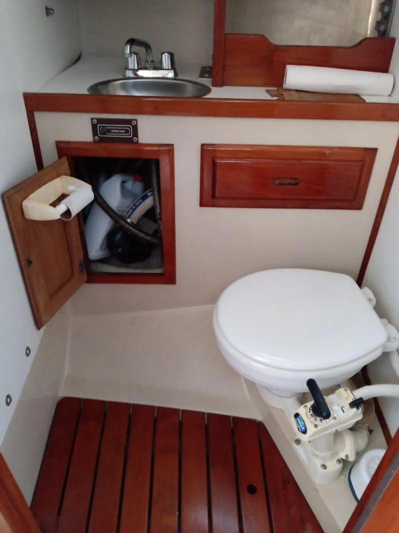 Slide: The Image of 1985 Catalina 38 boat bathroom with sink, toilet, and wooden cabinetry. - 10