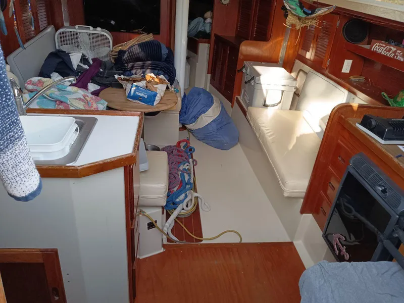 Slide: The Image of Interior of a 1985 Catalina 38 sailboat with cluttered living space and wooden cabinetry. - 5