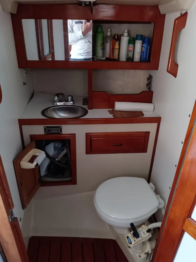 Slide: The Image of 1985 Catalina 38 boat bathroom with sink, toilet, and storage shelves. - 9