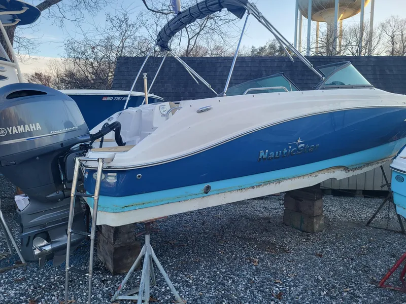 The Image of 2020 NauticStar 223DC Sport Deck boat with Yamaha outboard motor on a gravel lot. - 0