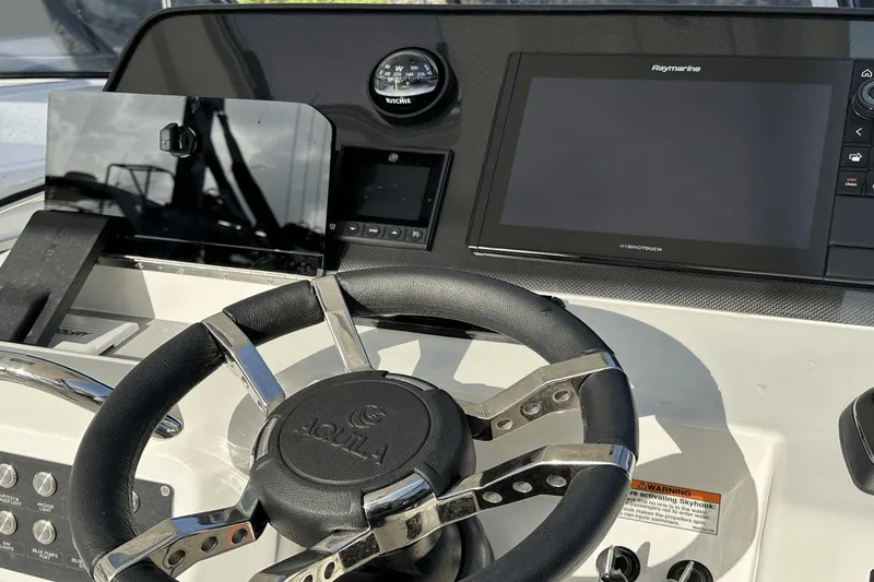 Slide: The Image of Steering console of 2023 Aquila 32 Sport with Raymarine display and Ritchie compass. - 18