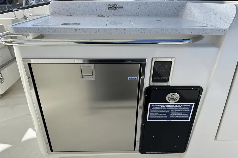 Slide: The Image of Aquila 32 Sport 2023 boat kitchen area with stainless steel appliances and Kenyon control panel. - 21