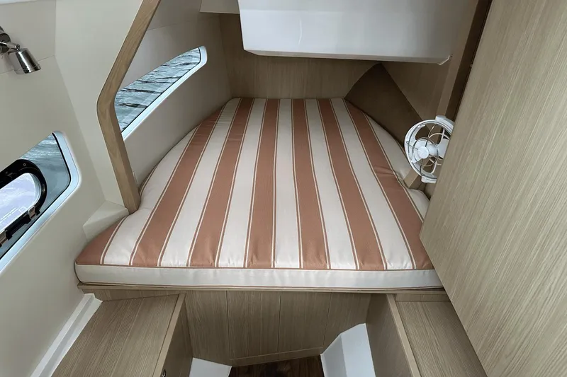 Slide: The Image of 2023 Aquila 32 Sport cabin with striped bed and porthole windows. - 22