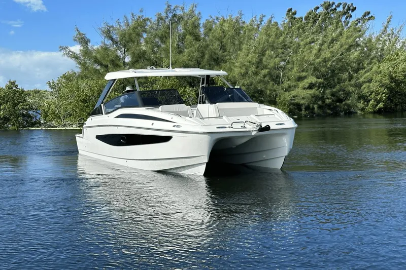 Slide: The Image of 2023 Aquila 32 Sport boat on calm water with lush greenery in the background. - 3