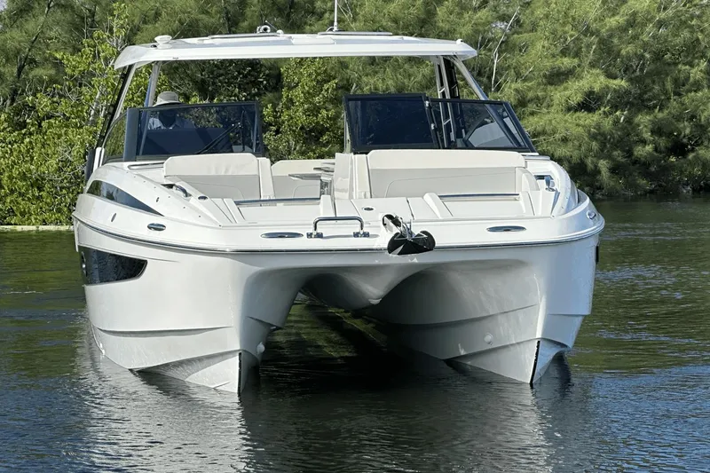 Slide: The Image of 2023 Aquila 32 Sport boat on calm water with lush greenery in the background. - 4