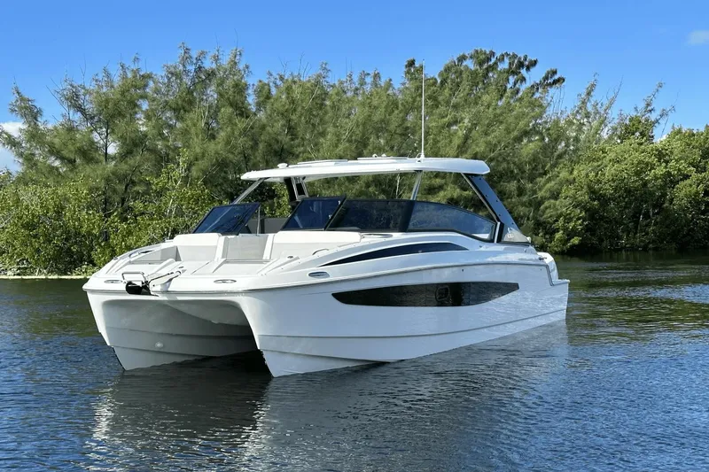 Slide: The Image of 2023 Aquila 32 Sport boat on calm water with lush greenery in the background. - 5