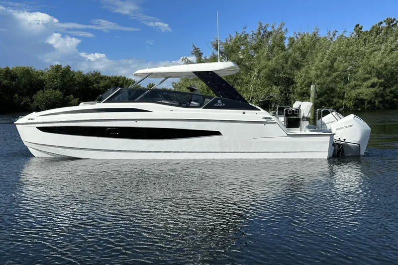 Slide: The Image of 2023 Aquila 32 Sport boat on calm water with lush greenery in the background. - 6