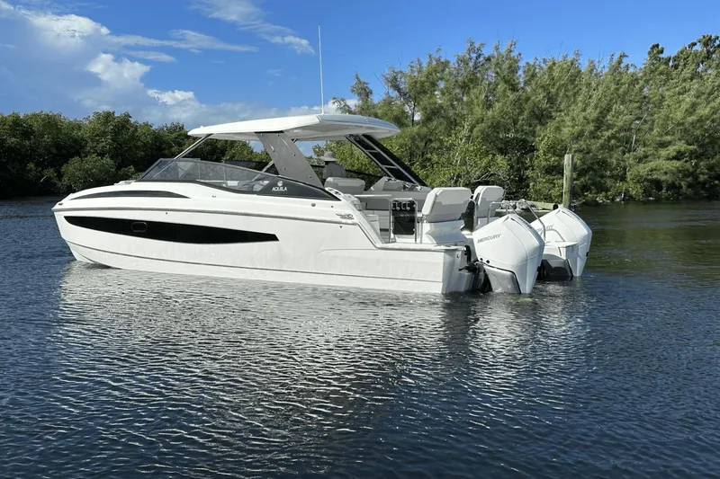 Slide: The Image of 2023 Aquila 32 Sport boat on calm water with lush greenery in the background. - 7
