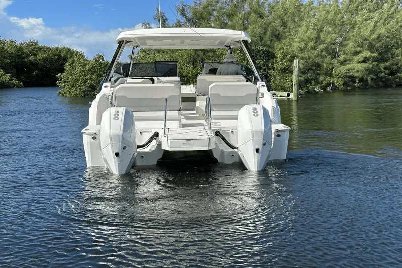 Slide: The Image of 2023 Aquila 32 Sport boat with dual outboard engines on a calm waterway. - 8