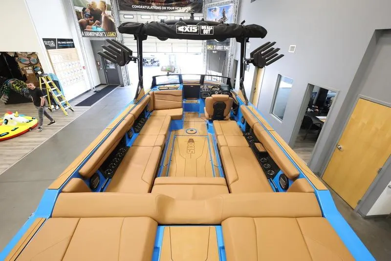 Slide: The Image of 2024 Axis T250 boat interior with tan seats and blue accents in showroom. - 10