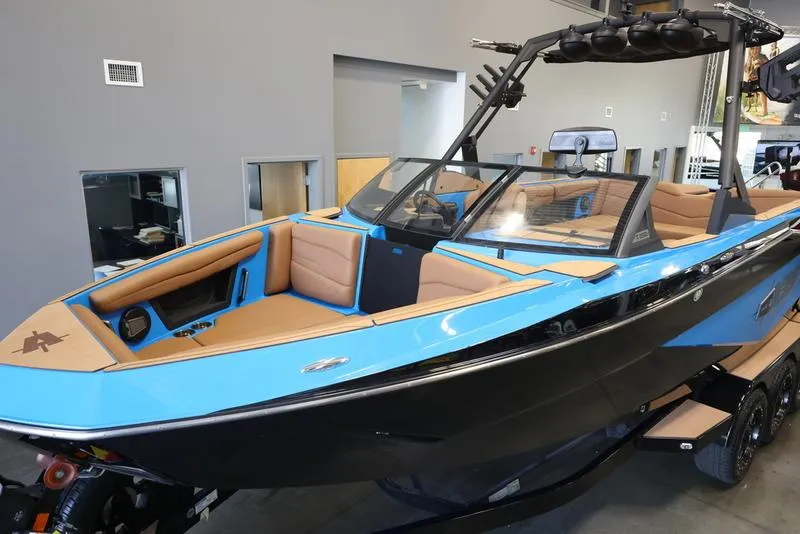 Slide: The Image of 2024 Axis T250 boat with blue and black exterior, tan interior, and wakeboard tower. - 14