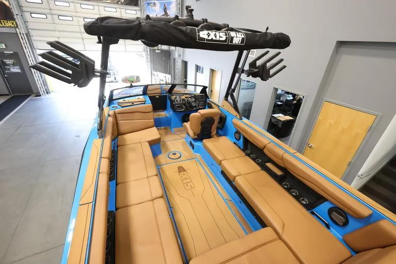Slide: The Image of 2024 Axis T250 boat interior with tan seating and blue accents in showroom. - 9