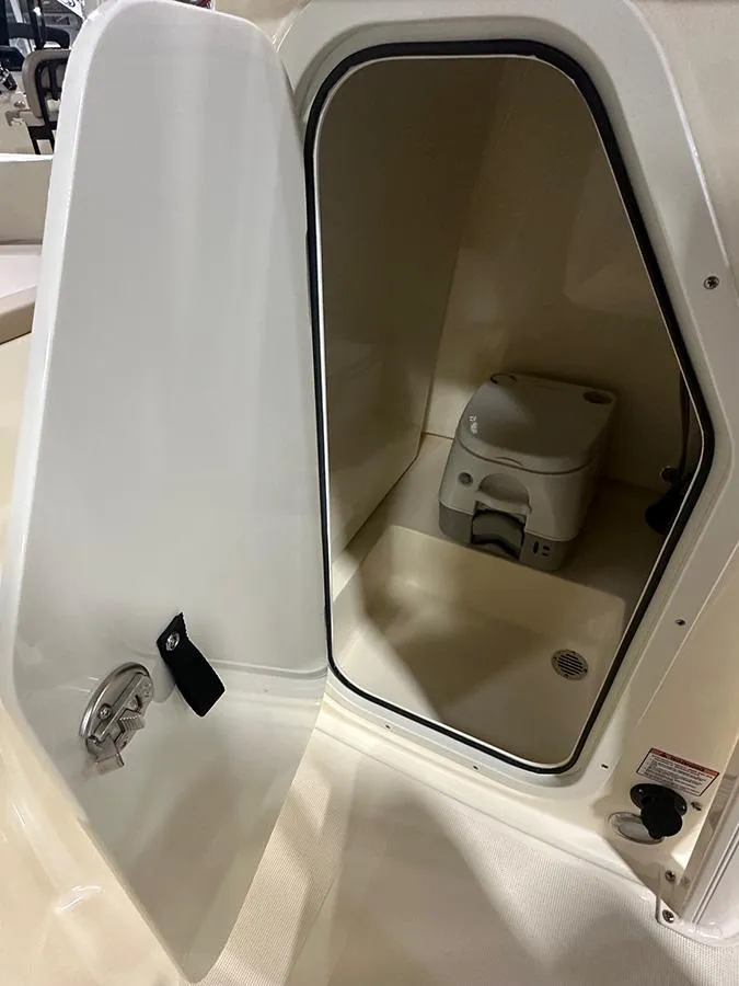 Slide: The Image of 2024 Scout 195 Sportfish boat interior with open storage compartment and portable toilet. - 7
