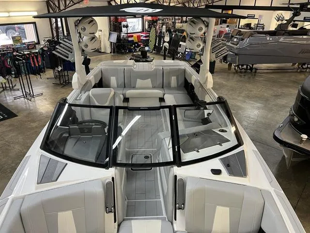 Slide: The Image of 2024 Malibu 24 MXZ boat interior with sleek seating and modern design in showroom. - 11