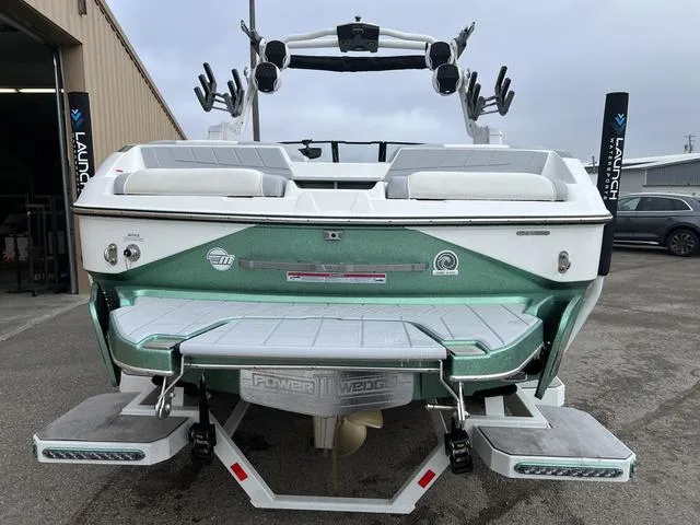 Slide: The Image of 2024 Malibu 24 MXZ boat, rear view, green and white, parked outdoors. - 4