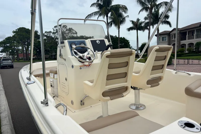 Slide: The Image of 2024 Scout 175 Sportfish boat with dual seats, steering console, and palm trees in the background. - 12
