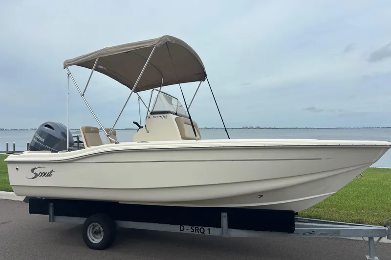 Slide: The Image of 2024 Scout 175 Sportfish boat with canopy on trailer by waterfront. - 3