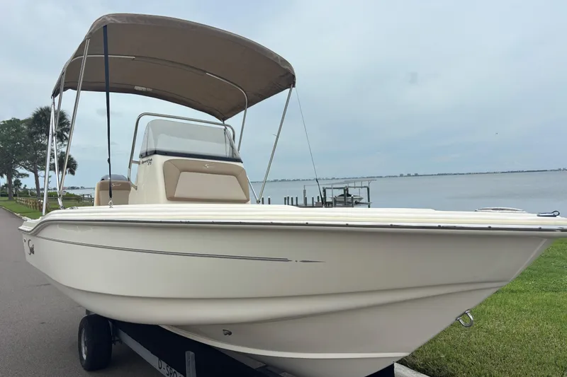 Slide: The Image of 2024 Scout 175 Sportfish boat with canopy, parked near a waterfront. - 5