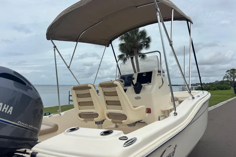Slide: The Image of 2024 Scout 175 Sportfish boat with Yamaha engine, docked near a scenic waterfront. - 6