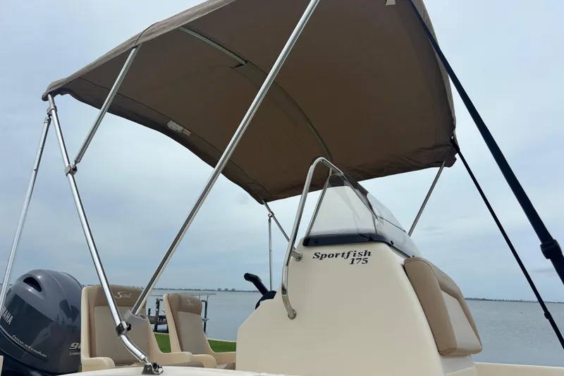 Slide: The Image of 2024 Scout 175 Sportfish boat with canopy and Yamaha engine, docked by the water. - 7