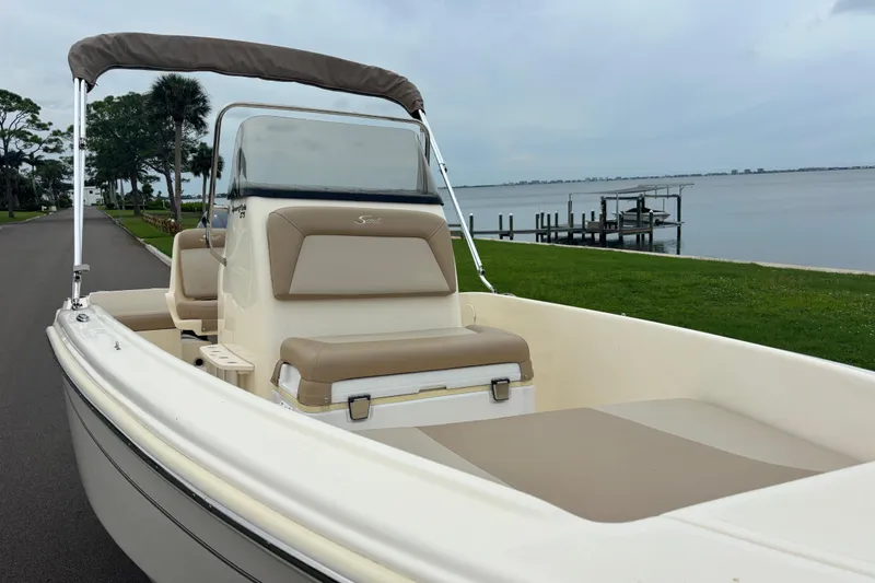 Slide: The Image of 2024 Scout 175 Sportfish boat by the waterfront, featuring beige seating and sleek design. - 8