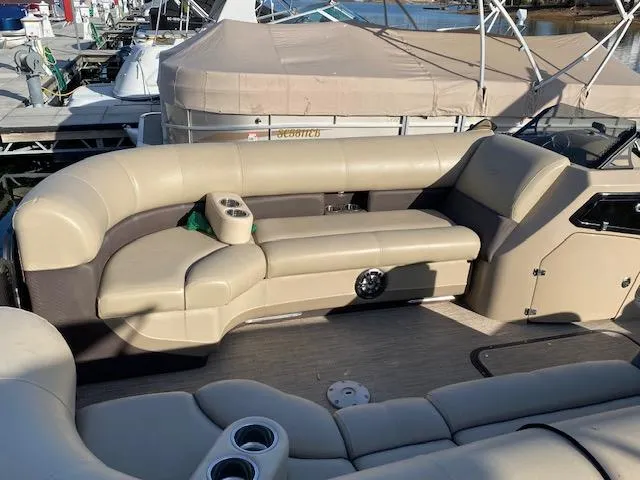 Slide: The Image of 2021 Manitou Oasis 25 SL VP Tritoon with beige seating and cup holders at a marina. - 9