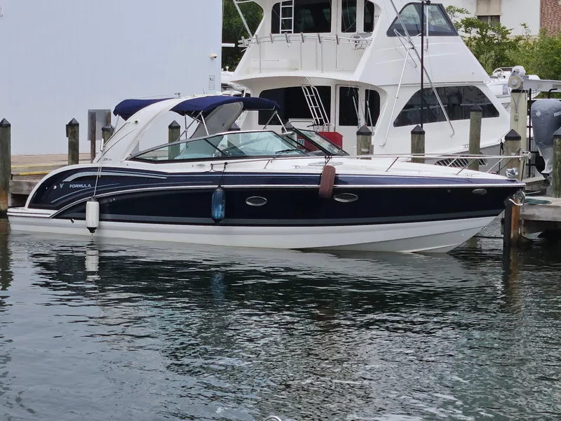 Slide: The Image of 2018 Formula 350 Sun Sport boat docked in marina, sleek design, blue and white exterior. - 5